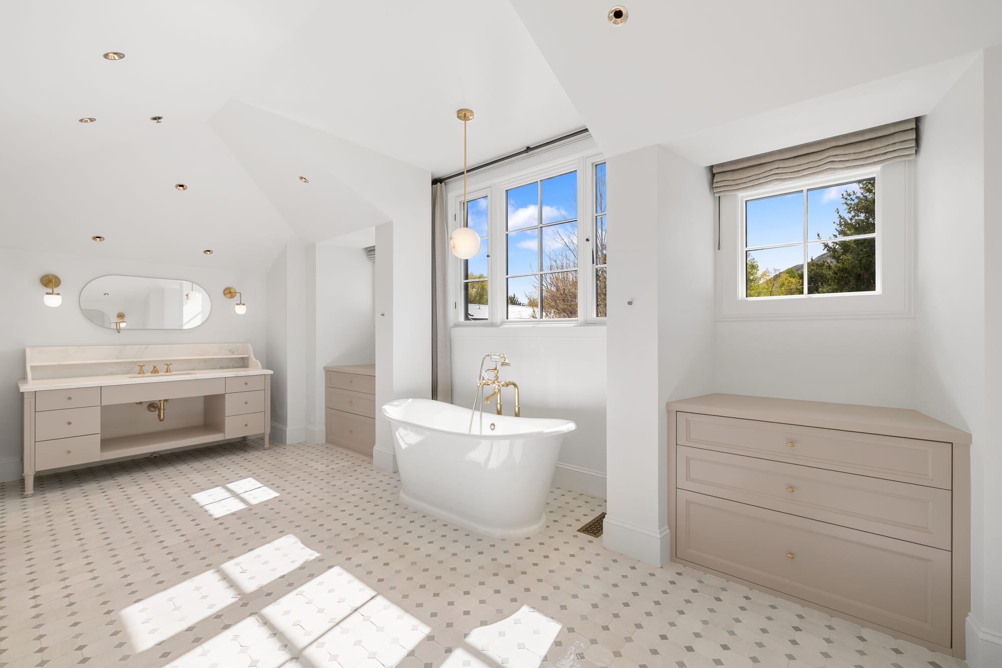Primary bath with freestanding tub, painted vanity and a built-in linen chest.