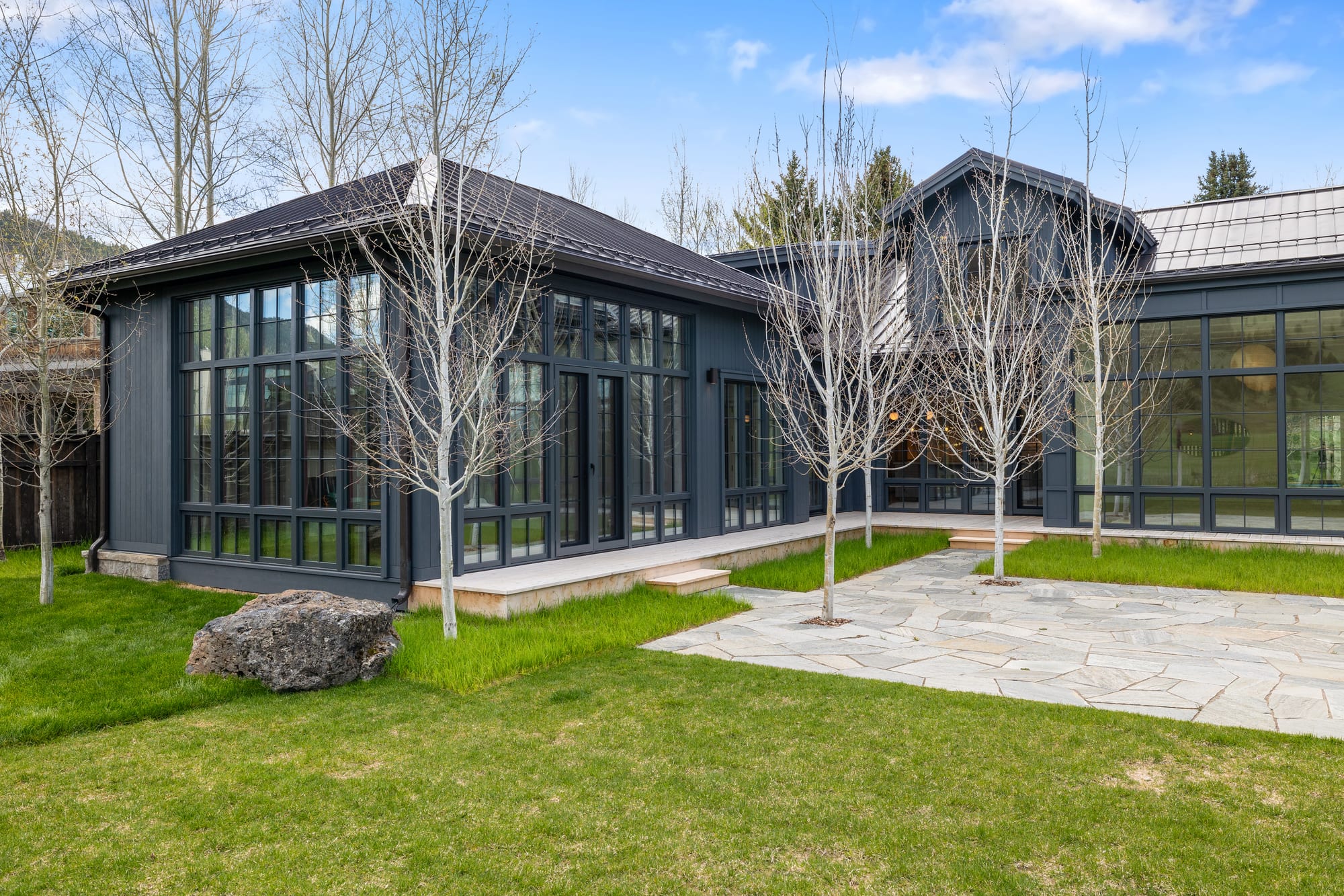 The glass-walled studio wing on the stone courtyard, under a standing-seam roof.