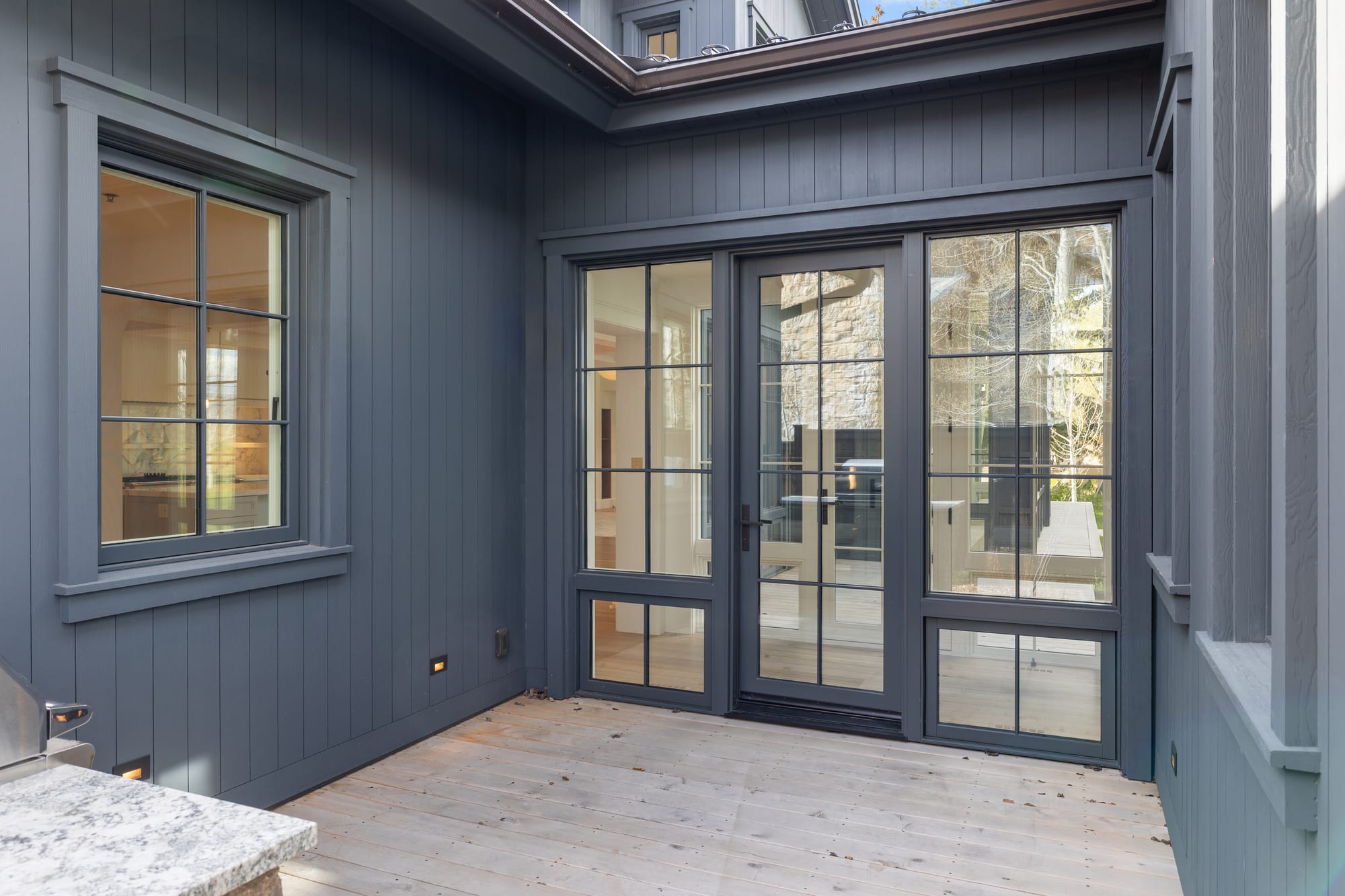 Covered outdoor kitchen with stone counter and steel doors to the courtyard.
