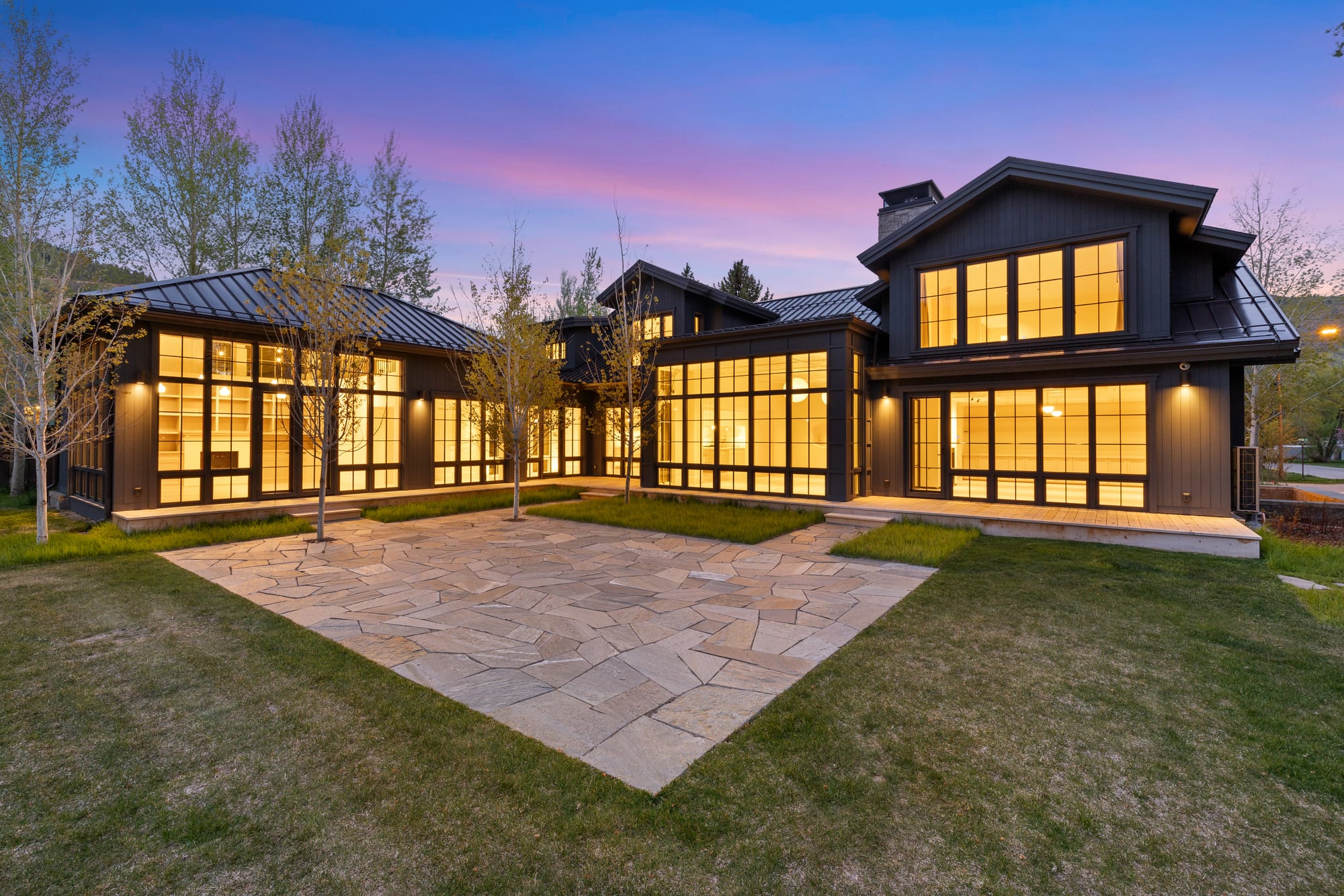 Dusk courtyard, flagstone terrace between two lit wings.