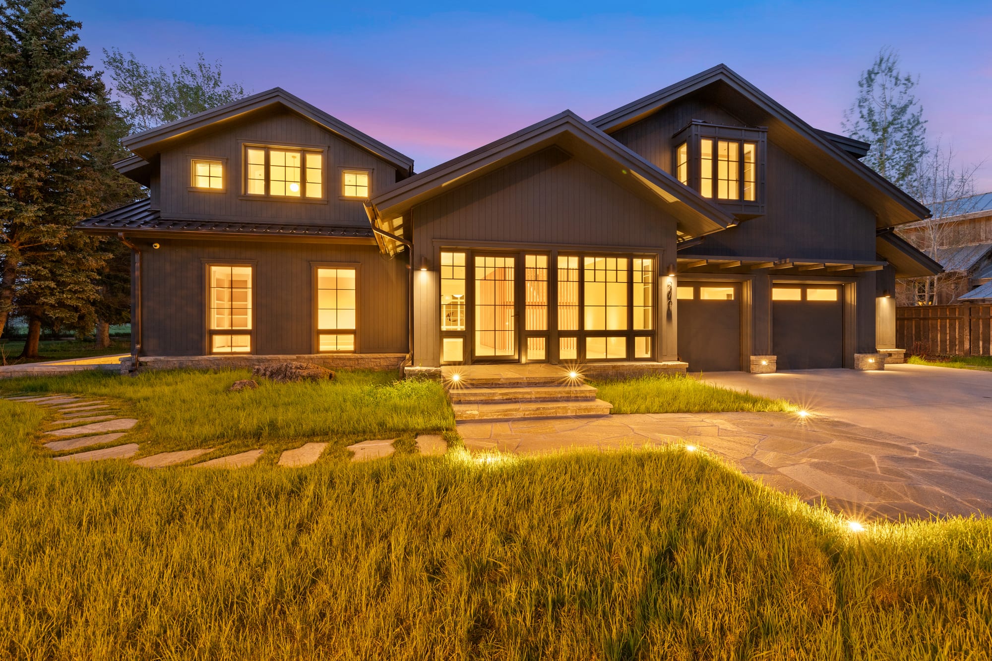 Front elevation at dusk with lit landscape and flagstone walk.