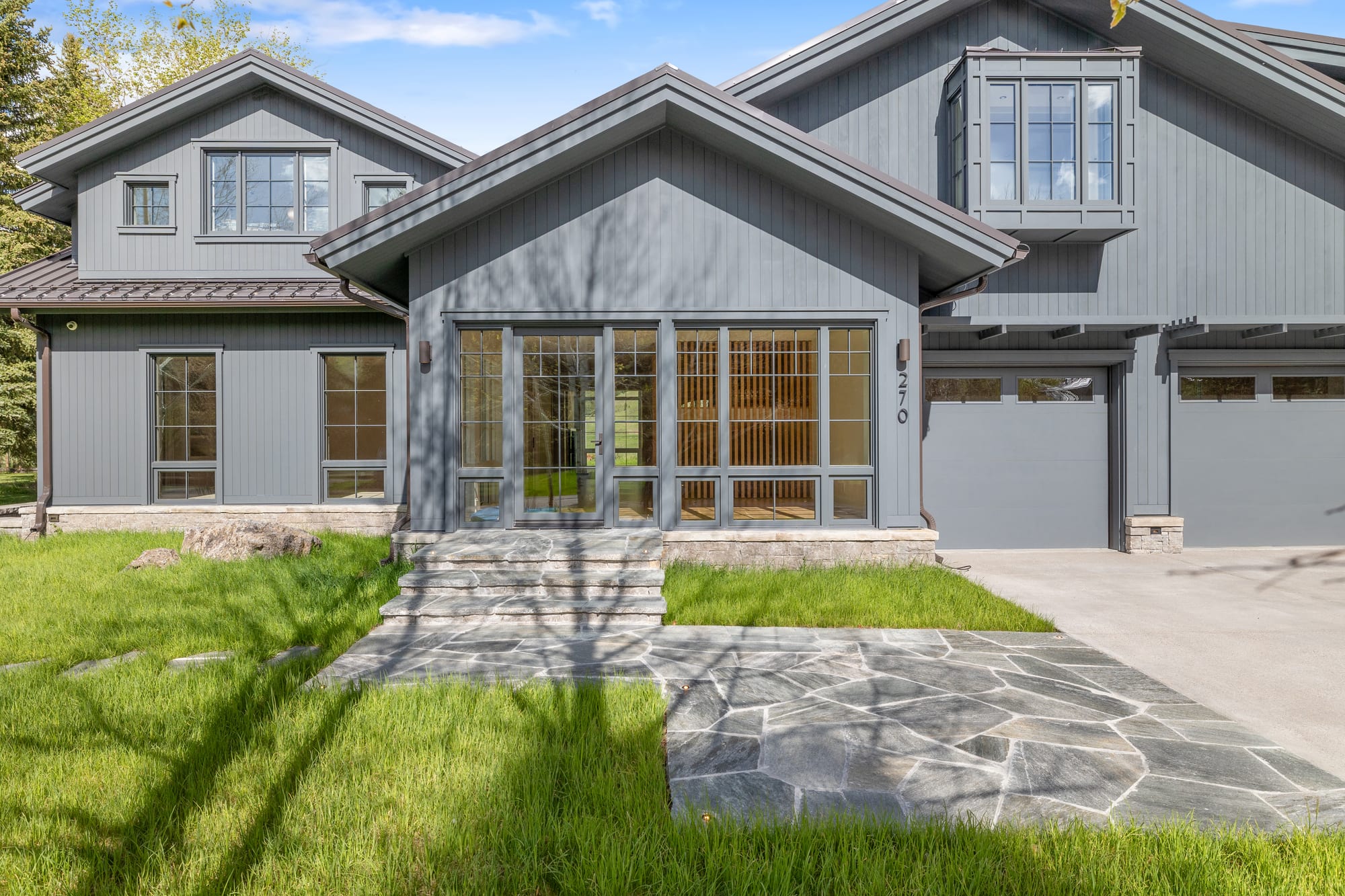 Front entry with stone walk and the lit slat wall visible through the glass.