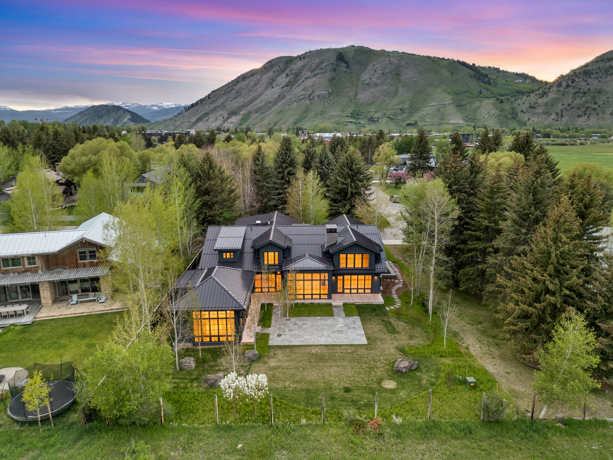 Dusk aerial over the valley with the house at center.