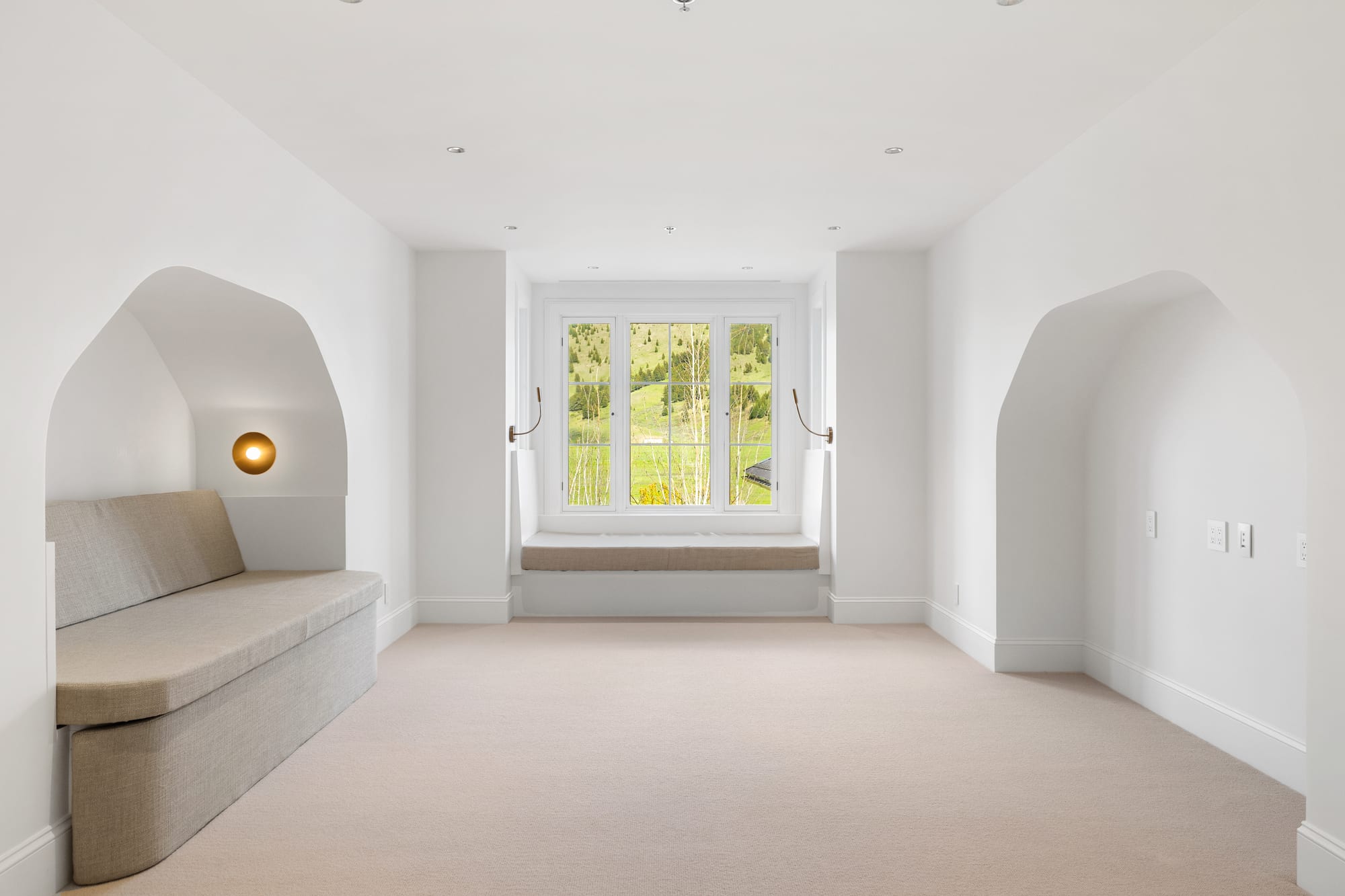 Guest loft with arched alcoves and an upholstered window bench.
