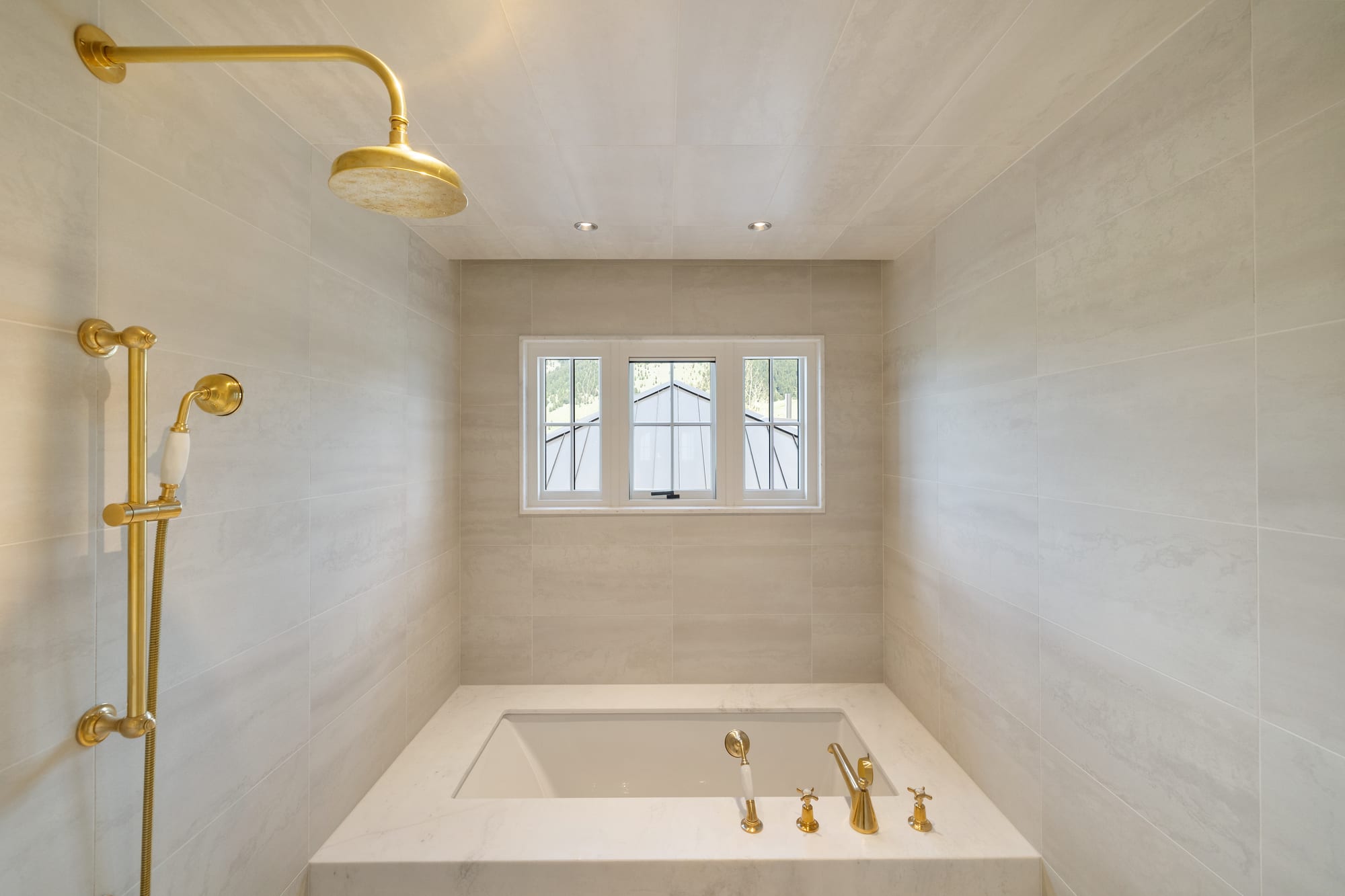 Guest bath with a drop-in tub in a large-format stone alcove and brass fittings.