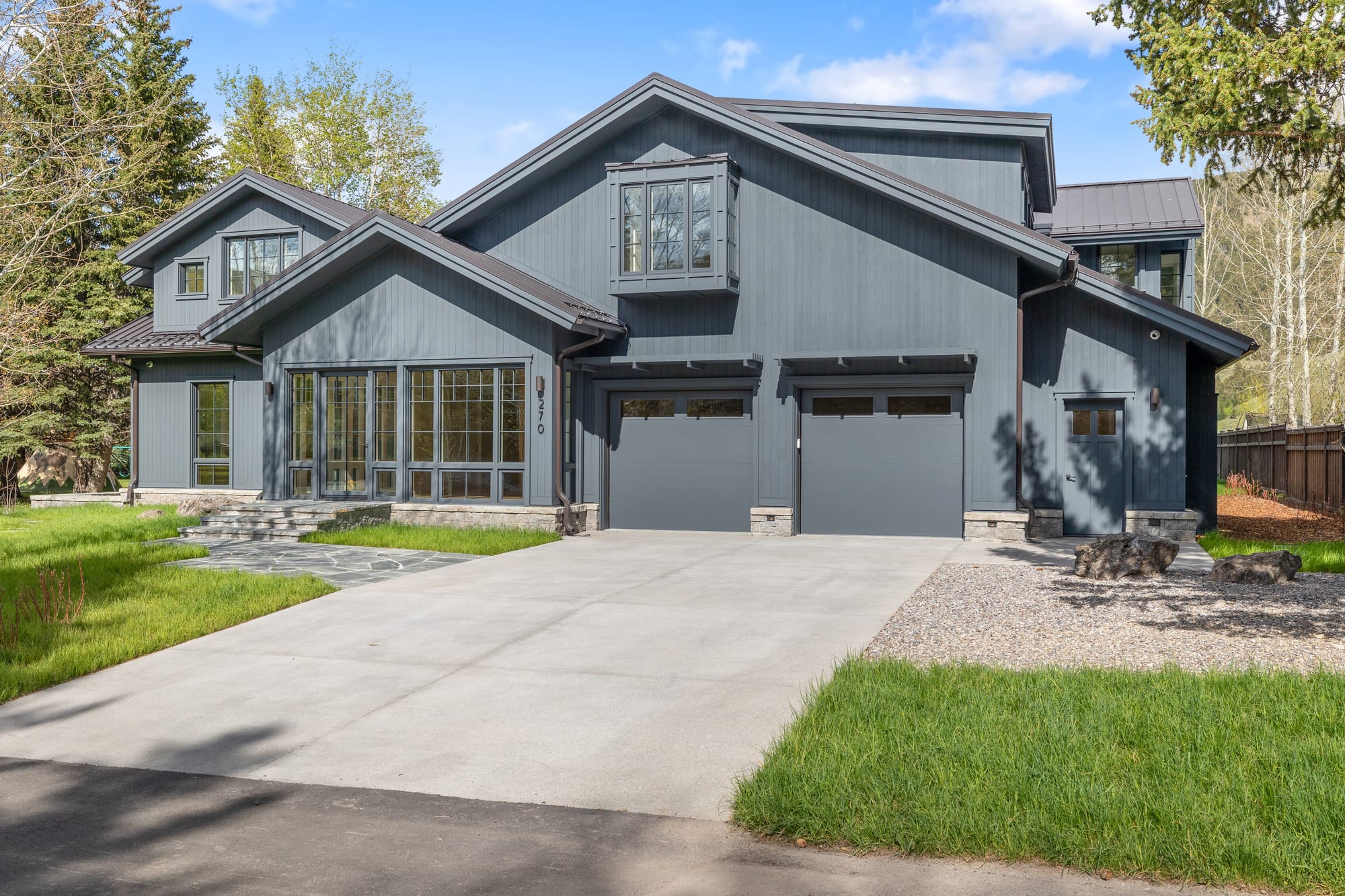 Front elevation and drive — gabled farmhouse volumes with steel window walls.