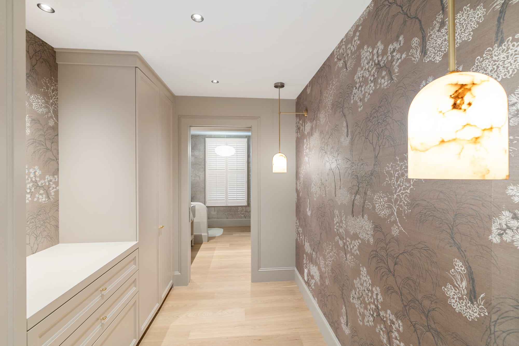 Mudroom bench and drawer bank in painted cabinetry beneath an alabaster pendant.