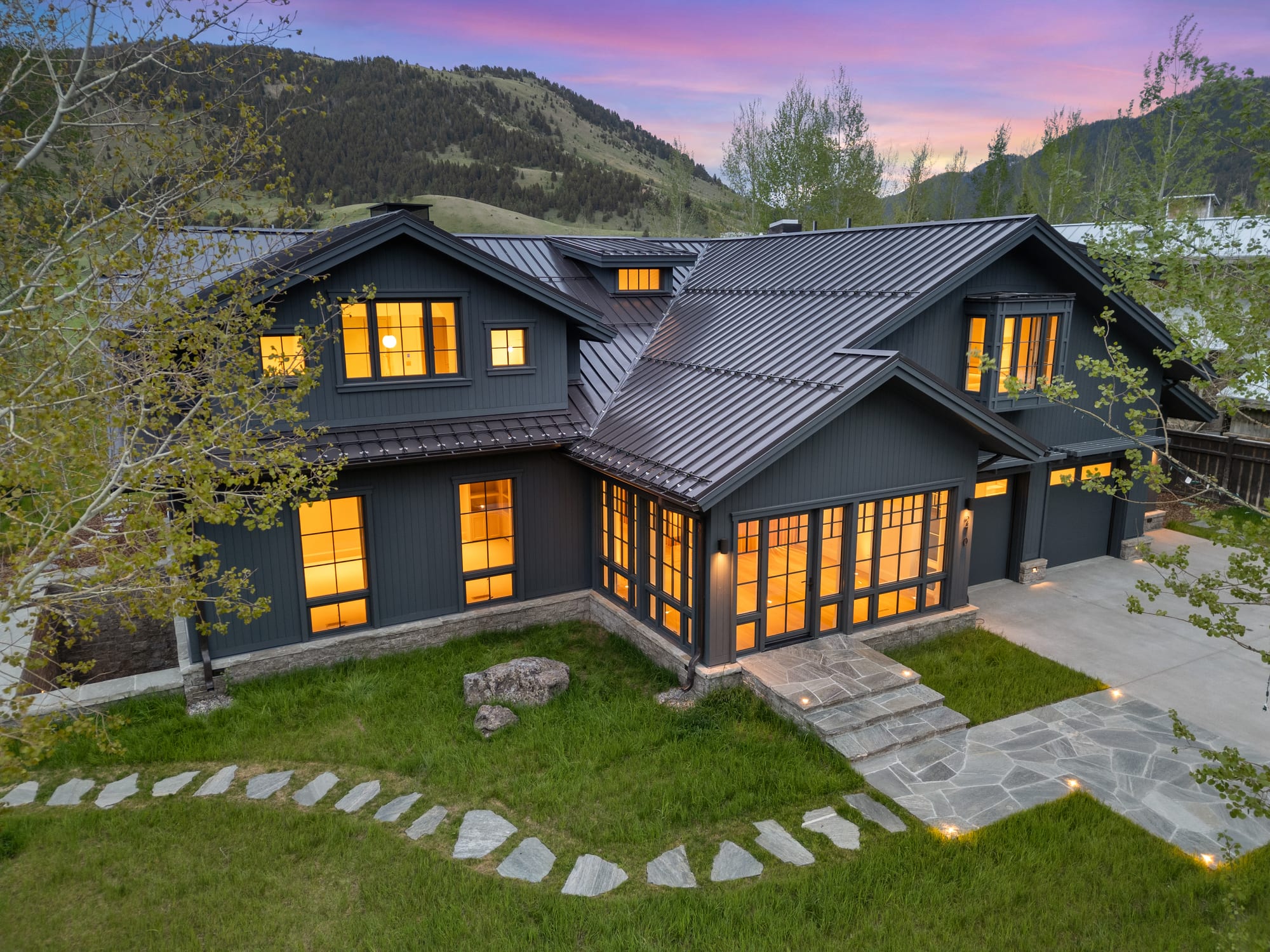 Dusk aerial of the front elevation with the lit flagstone walk.