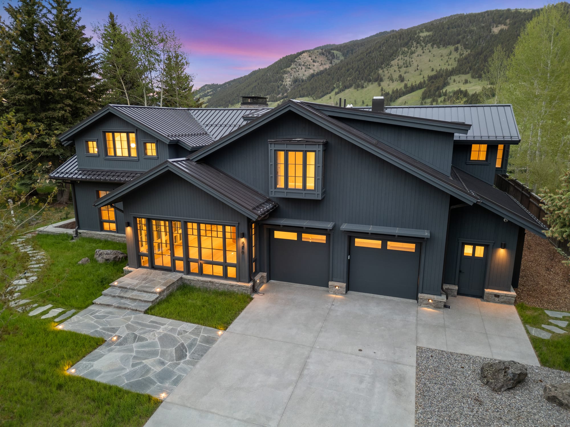 Dusk front elevation with the garage wing and stone drive court.