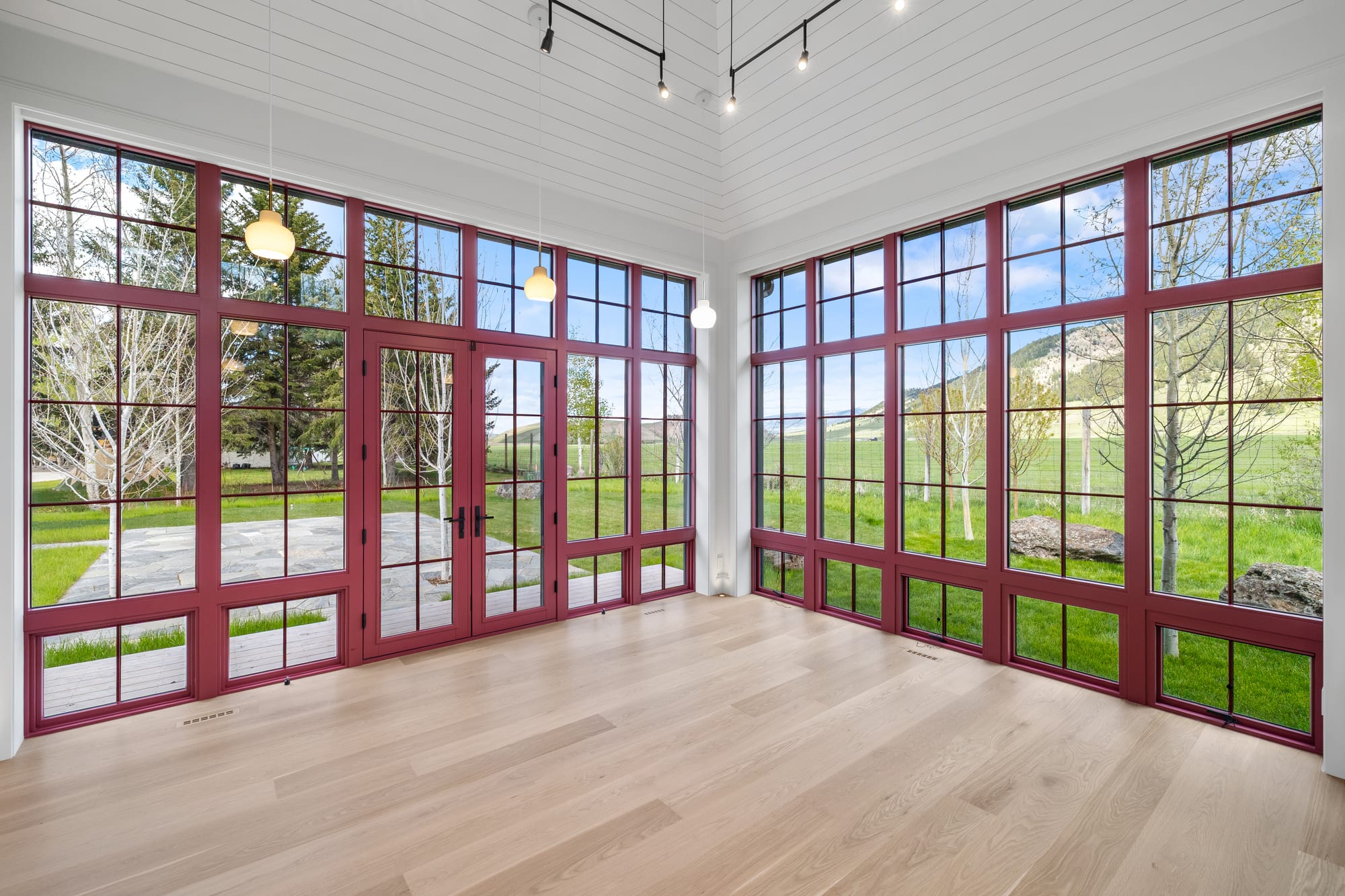 Sun room with cranberry steel window walls, shiplap ceiling and white oak floors.