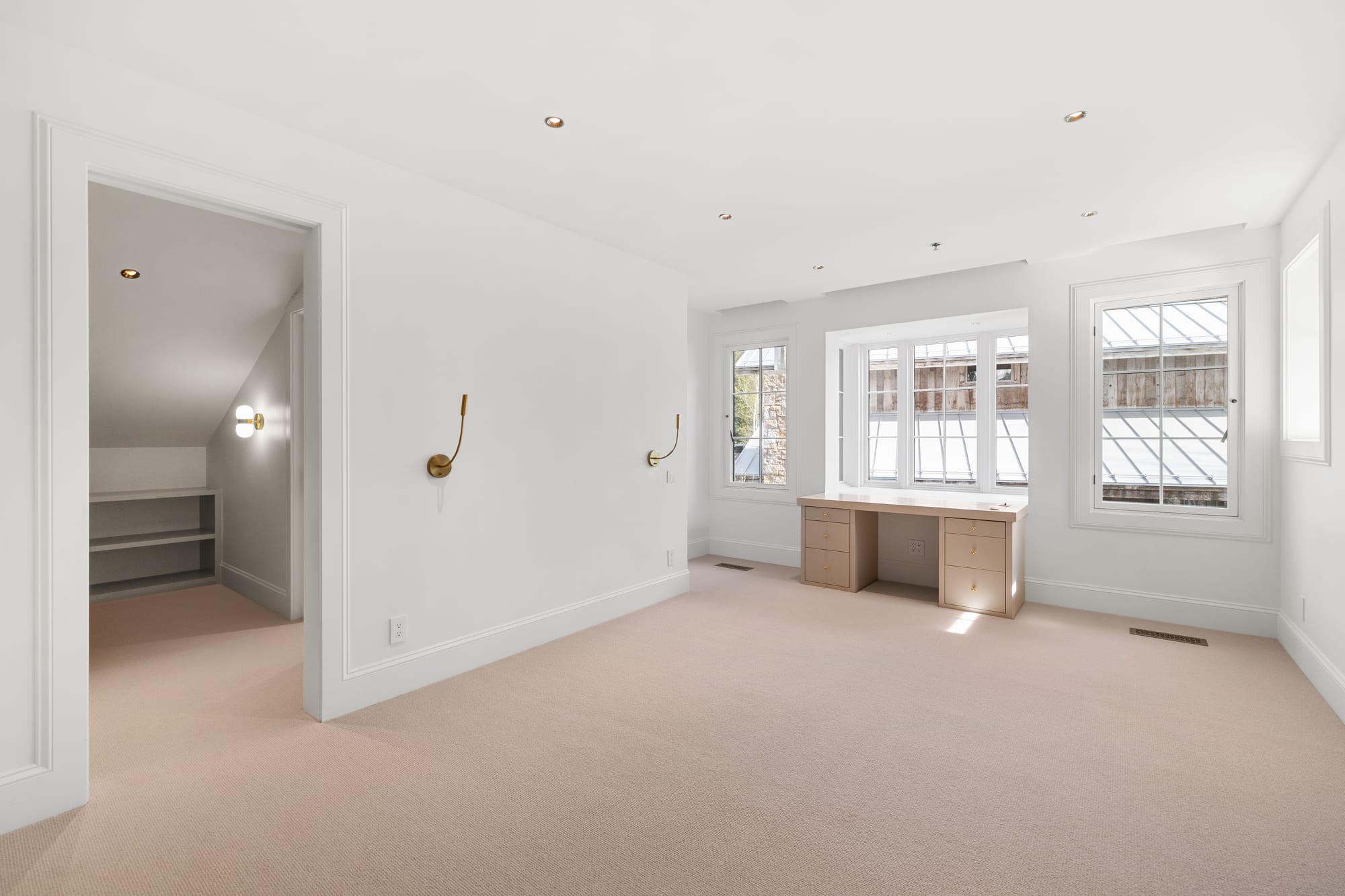 Bedroom with a built-in white oak desk beneath a bank of windows.