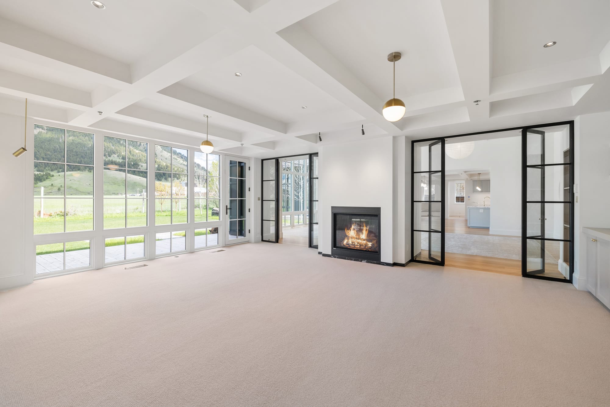 Coffered great room opening to the refuge through steel doors and a full window wall.
