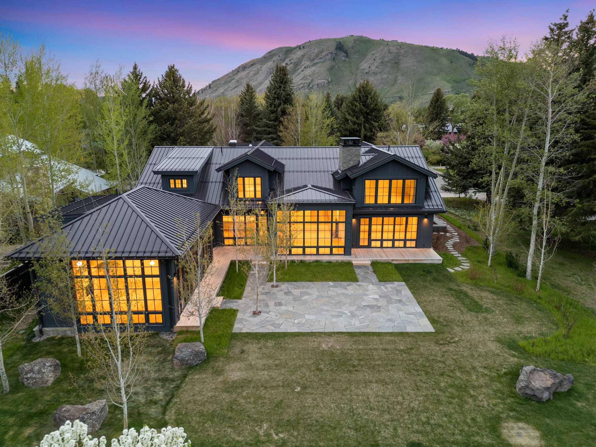 Dusk aerial with the house set against the mountain.