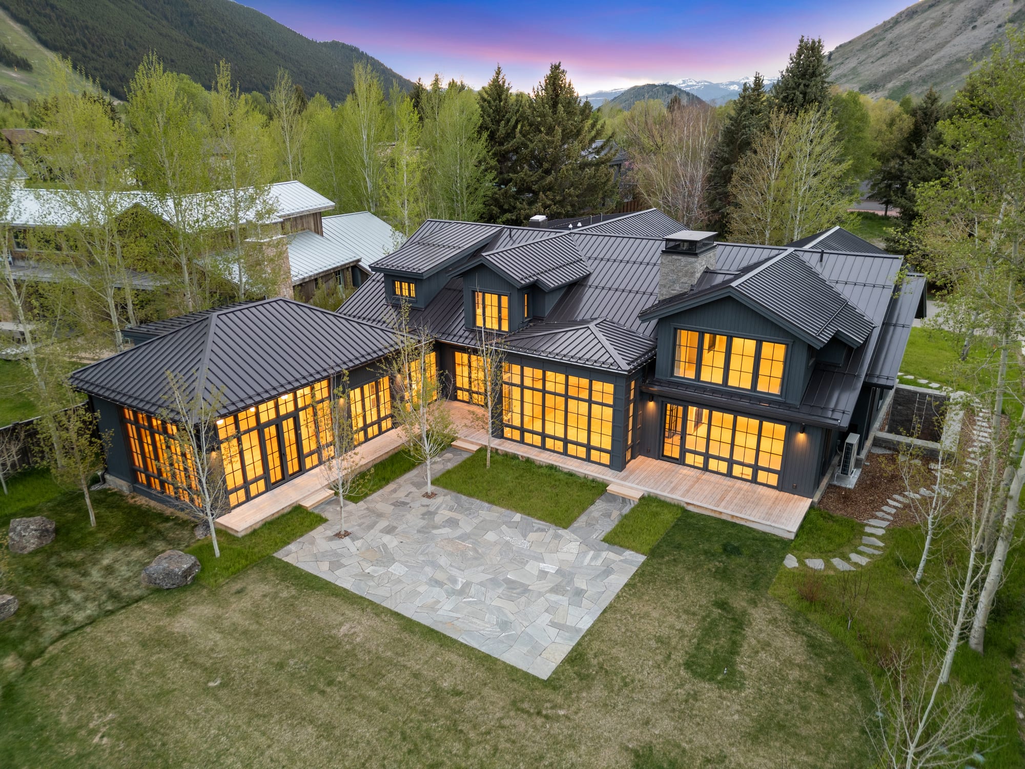 Dusk aerial showing the courtyard plan and standing-seam roofs.