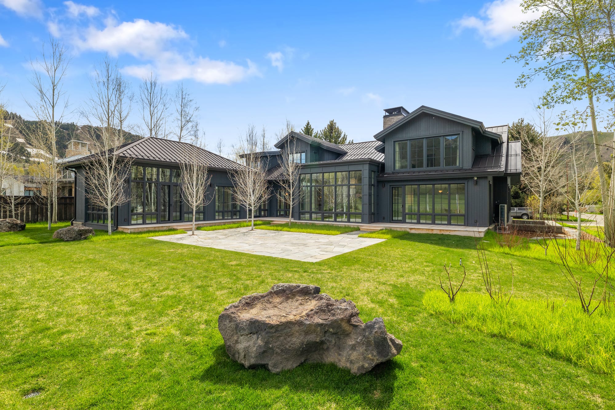 Courtyard elevation — farmhouse massing in charcoal board-and-batten over flagstone.