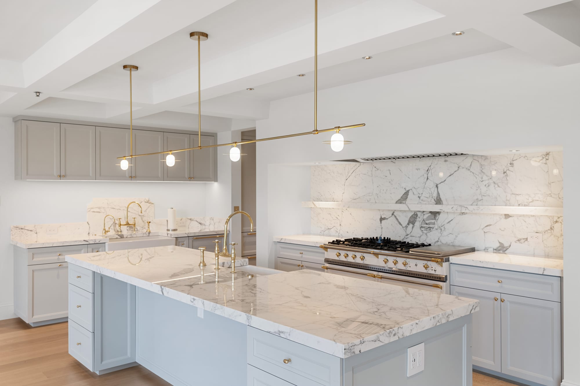 Kitchen with marble slab backsplash, floating marble shelf and brass range trim.