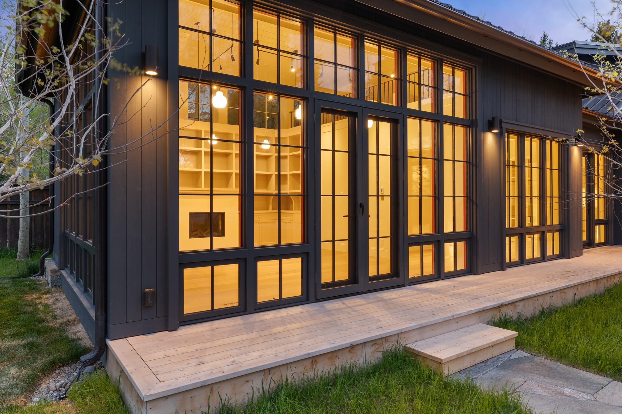 Library wing at dusk, cedar deck and steel doors onto the courtyard.